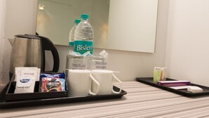 A hotel room with a tray containing a Bisleri water bottle, a coffee pot, a pack of Nescafe coffee, a pack of cigarettes, and a tray of toiletries. - Hotel Vijay Fablis (Coimbatore)