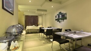 A hotel dining area with tables, chairs, and buffet service. - Hotel Vijay Fablis (Coimbatore)