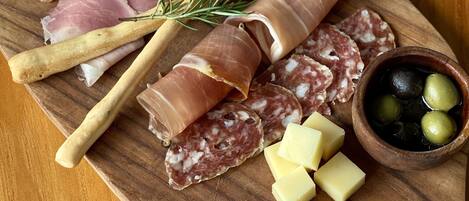 Una tabla de madera con diversos tipos de carne, queso y aceitunas.