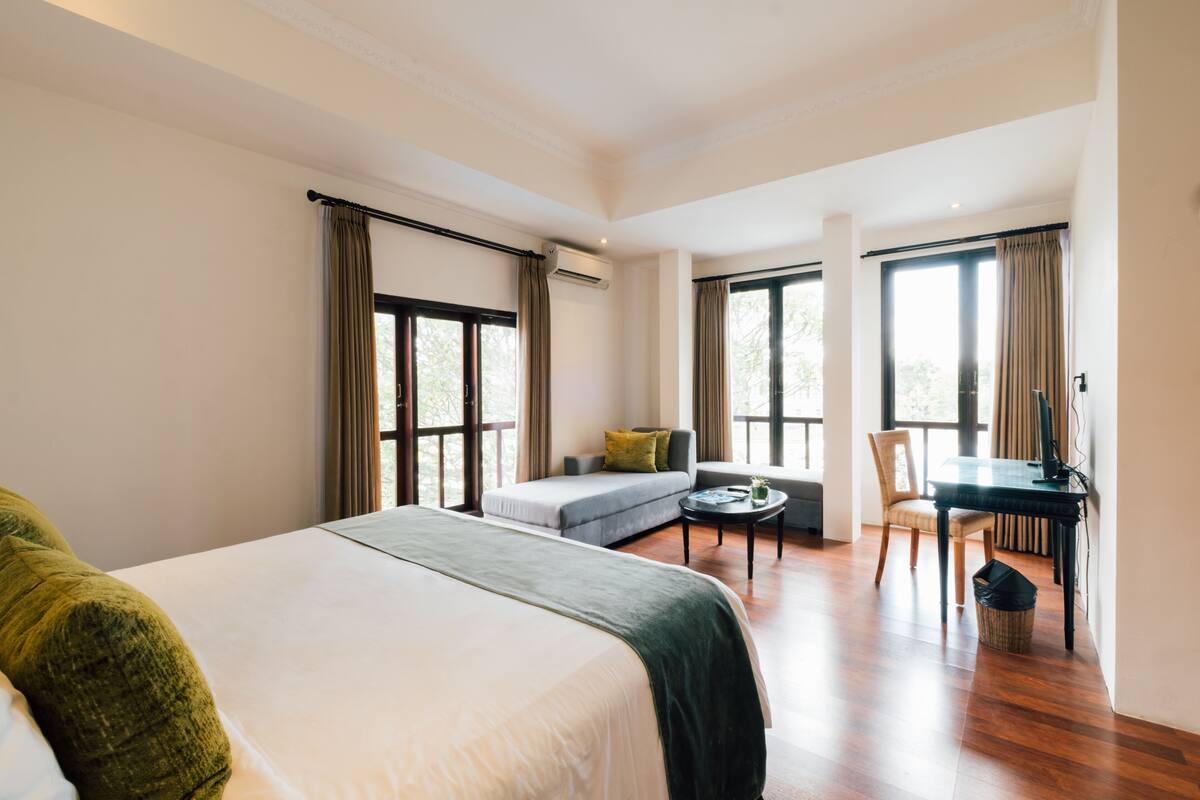 A hotel room with a large bed, a sofa, a desk, and a chair.