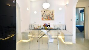 Un comedor moderno con una mesa de vidrio, sillas transparentes y un banco blanco.