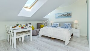 Ett sovrum med ett takfönster, en säng med mönstrade kuddar, ett sängbord med en lampa och en tavla på väggen.