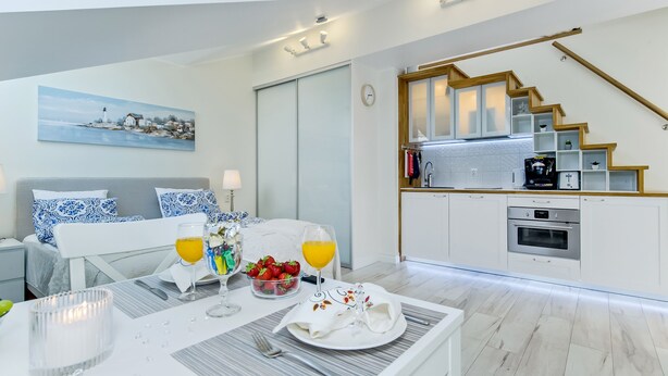 Ett modernt hotellrum med matplats, kök och en trappa.