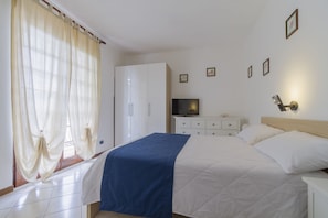 Une chambre à coucher avec un lit, une télévision, une armoire et une table de chevet.