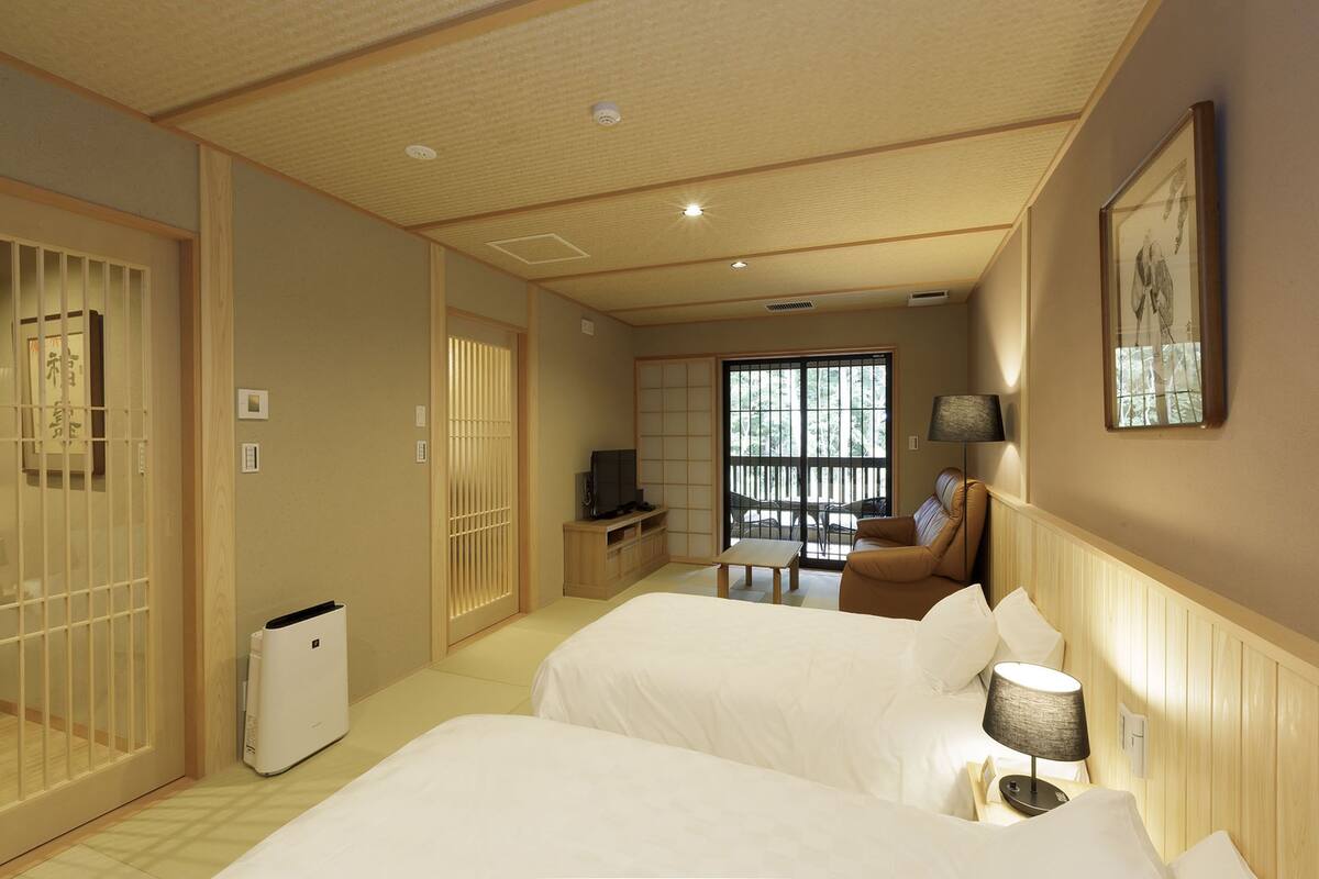 Une chambre d’hôtel avec deux lits, une télévision, un bureau et une vue sur l’extérieur.