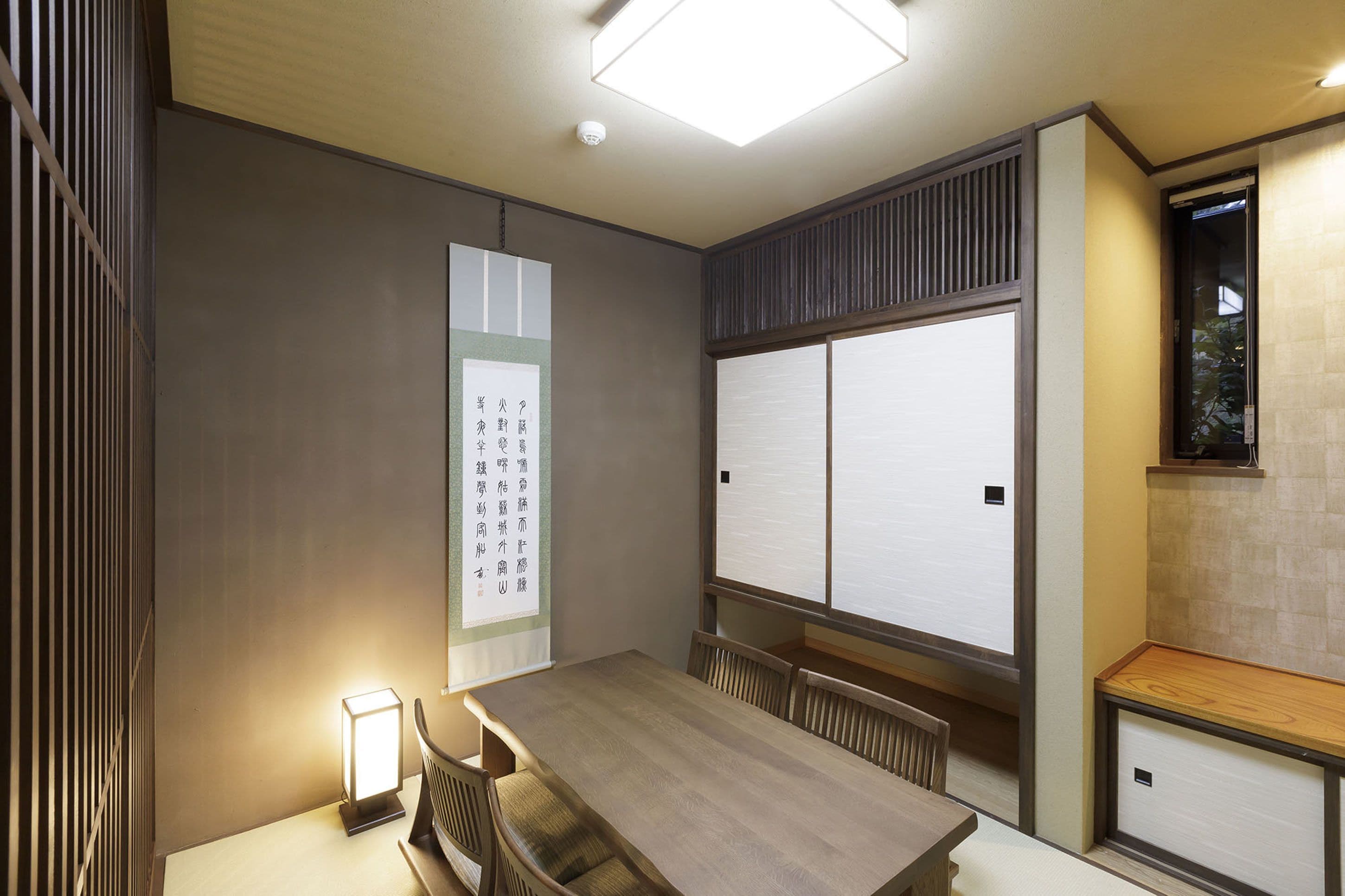 A traditional Japanese-style room with tatami flooring, a low wooden table, and sliding shoji screens.