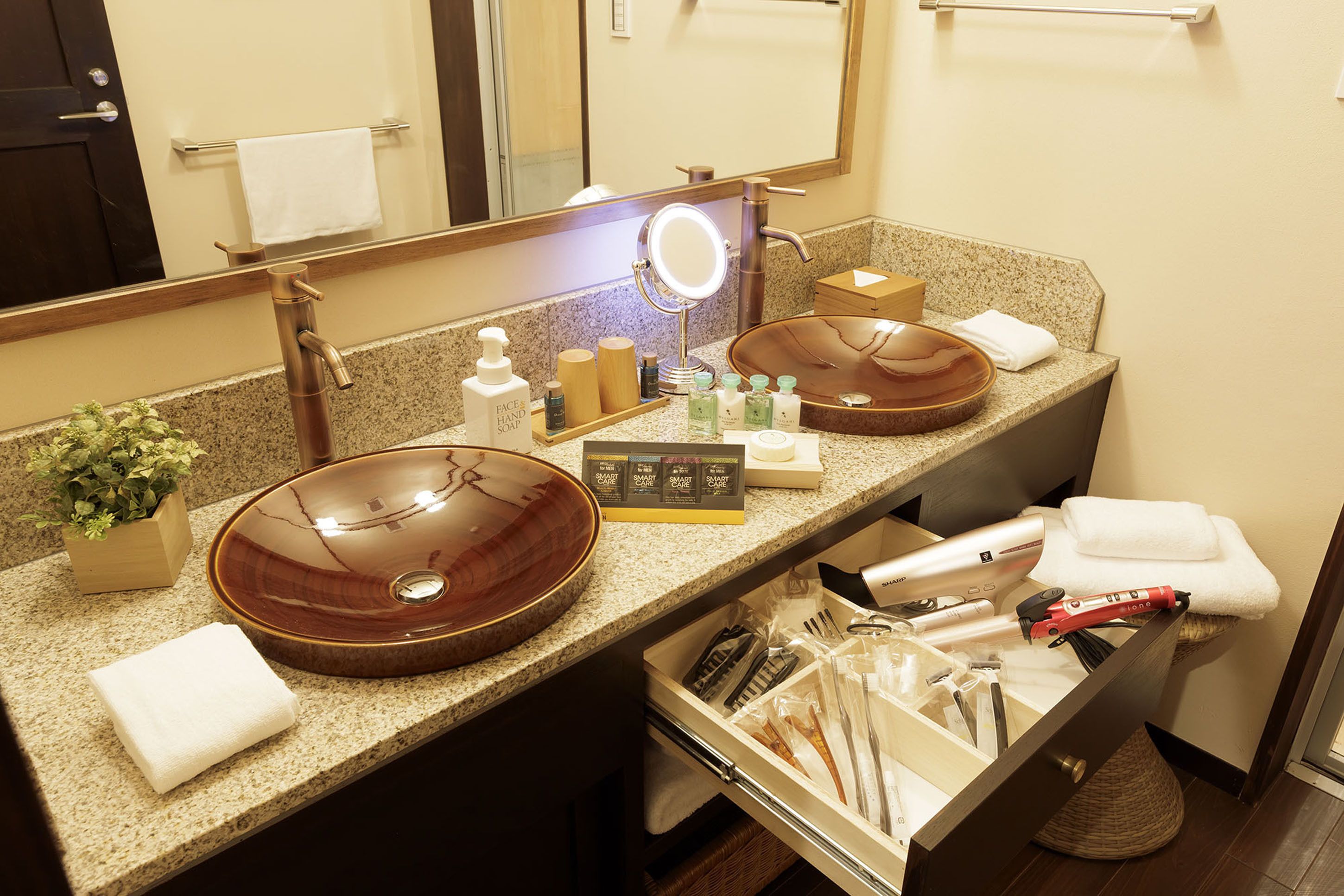 Un baño con dos lavamanos, un espejo y un mueble de tocador con artículos de aseo.