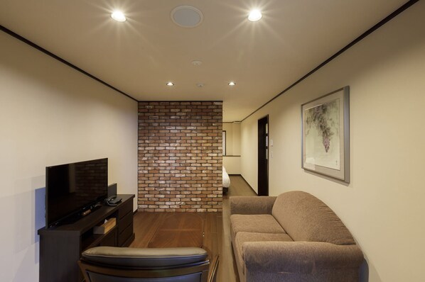 Een moderne woonkamer met een flatscreen televisie, een bank, een salontafel en een accentmuur van baksteen.