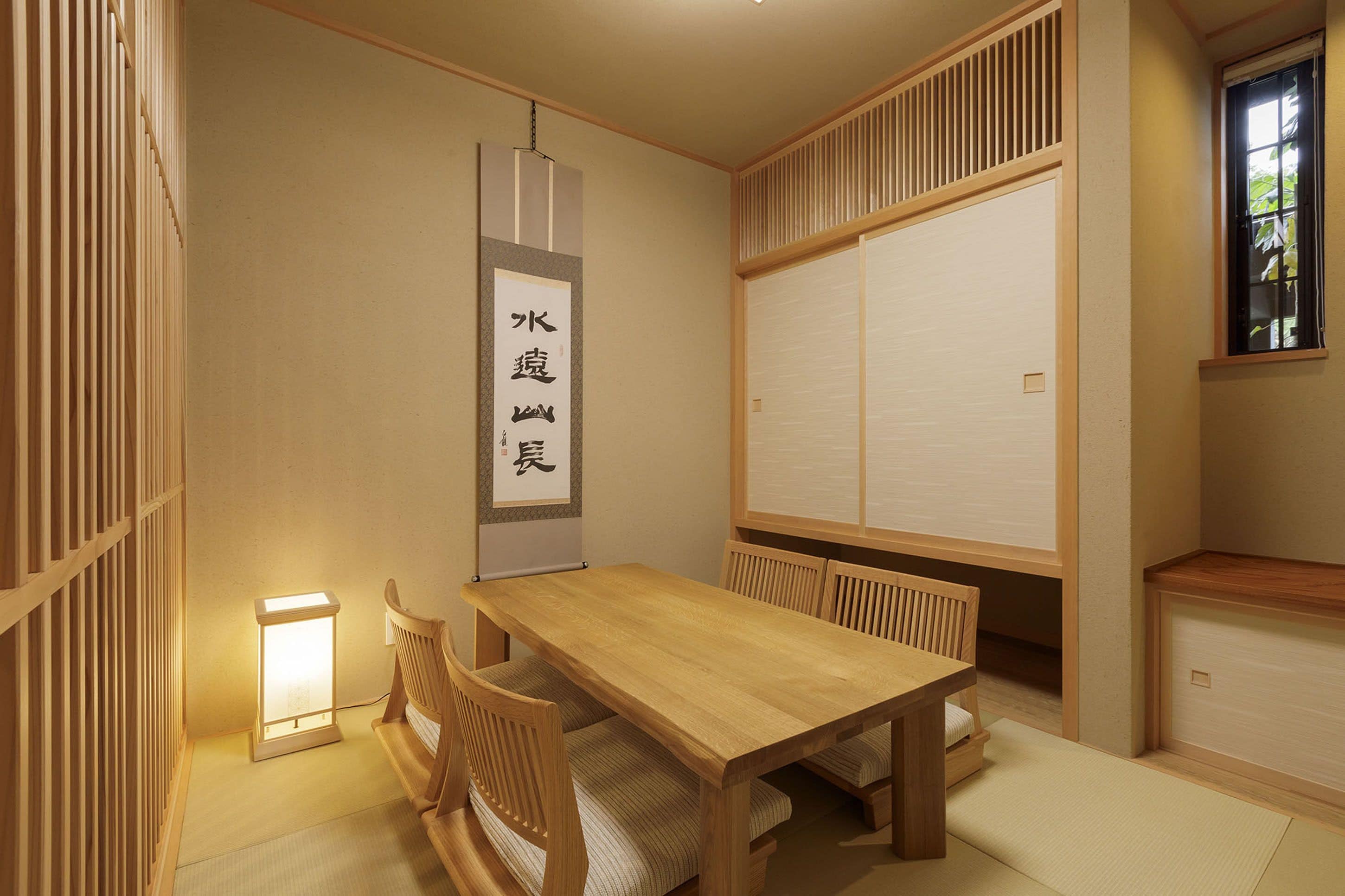 Una habitación japonesa tradicional con suelo de tatami, una mesa de madera baja y una puerta corredera tipo shoji.