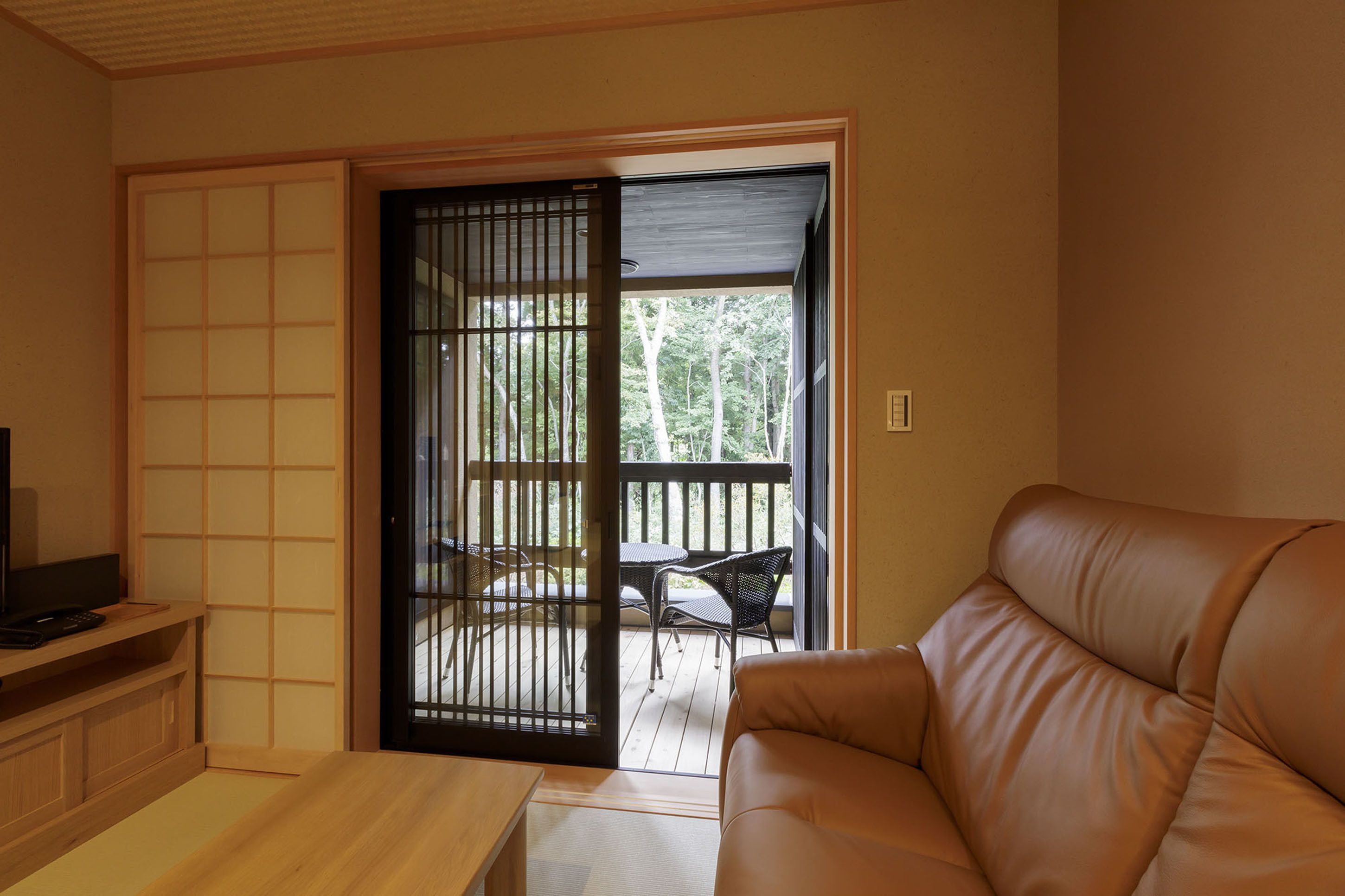 A room with a sliding door leading to an outdoor balcony with a table and chairs.