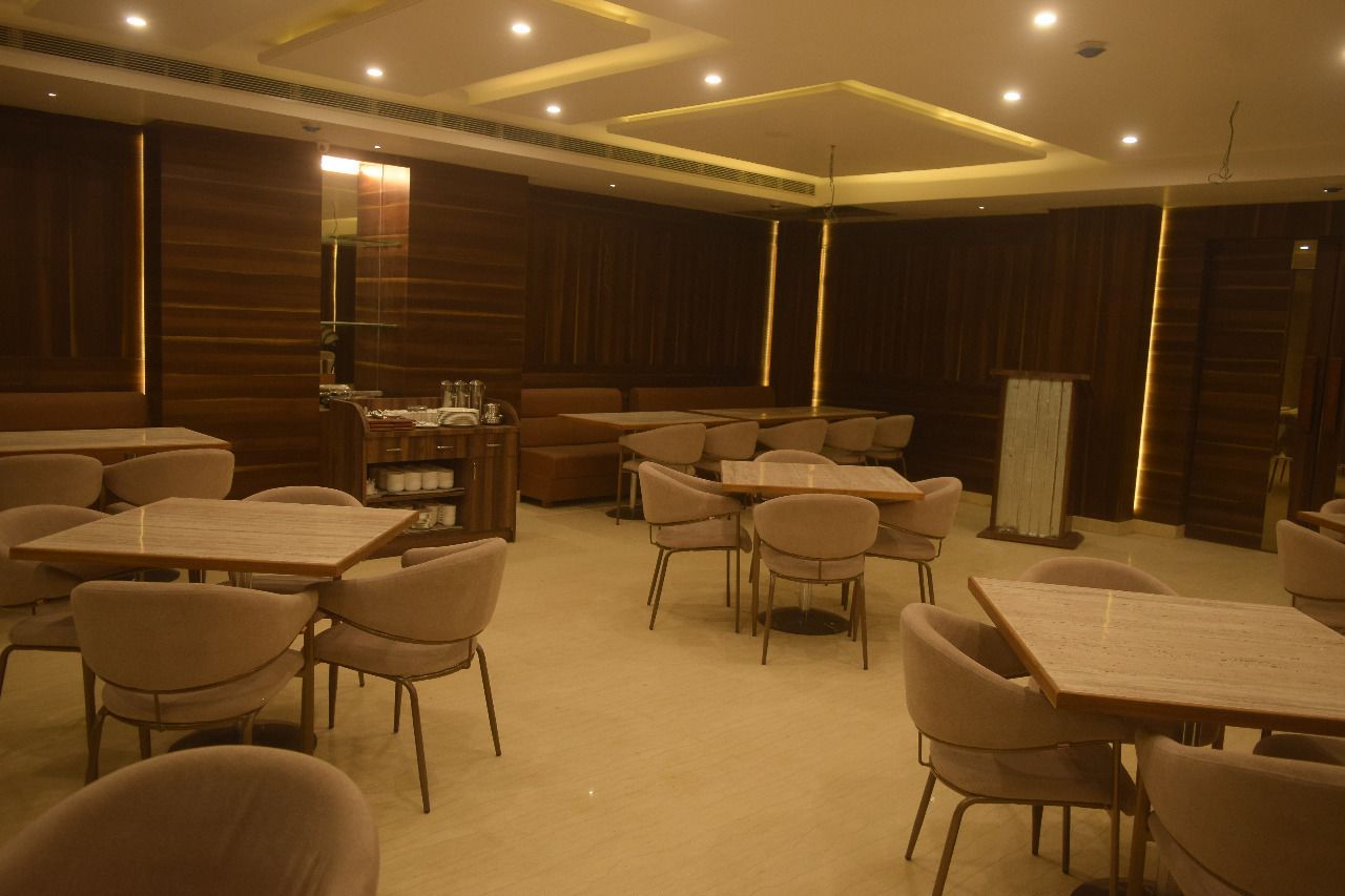 A spacious dining area with multiple tables and chairs, wooden paneling on the walls, and recessed lighting.