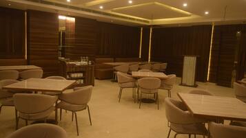 A spacious dining area with multiple tables and chairs, wooden paneling on the walls, and recessed lighting.