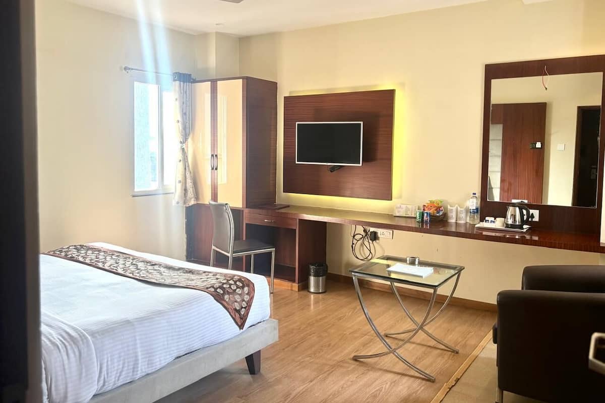 A hotel room with a bed, desk, chair, TV, and a large mirror.