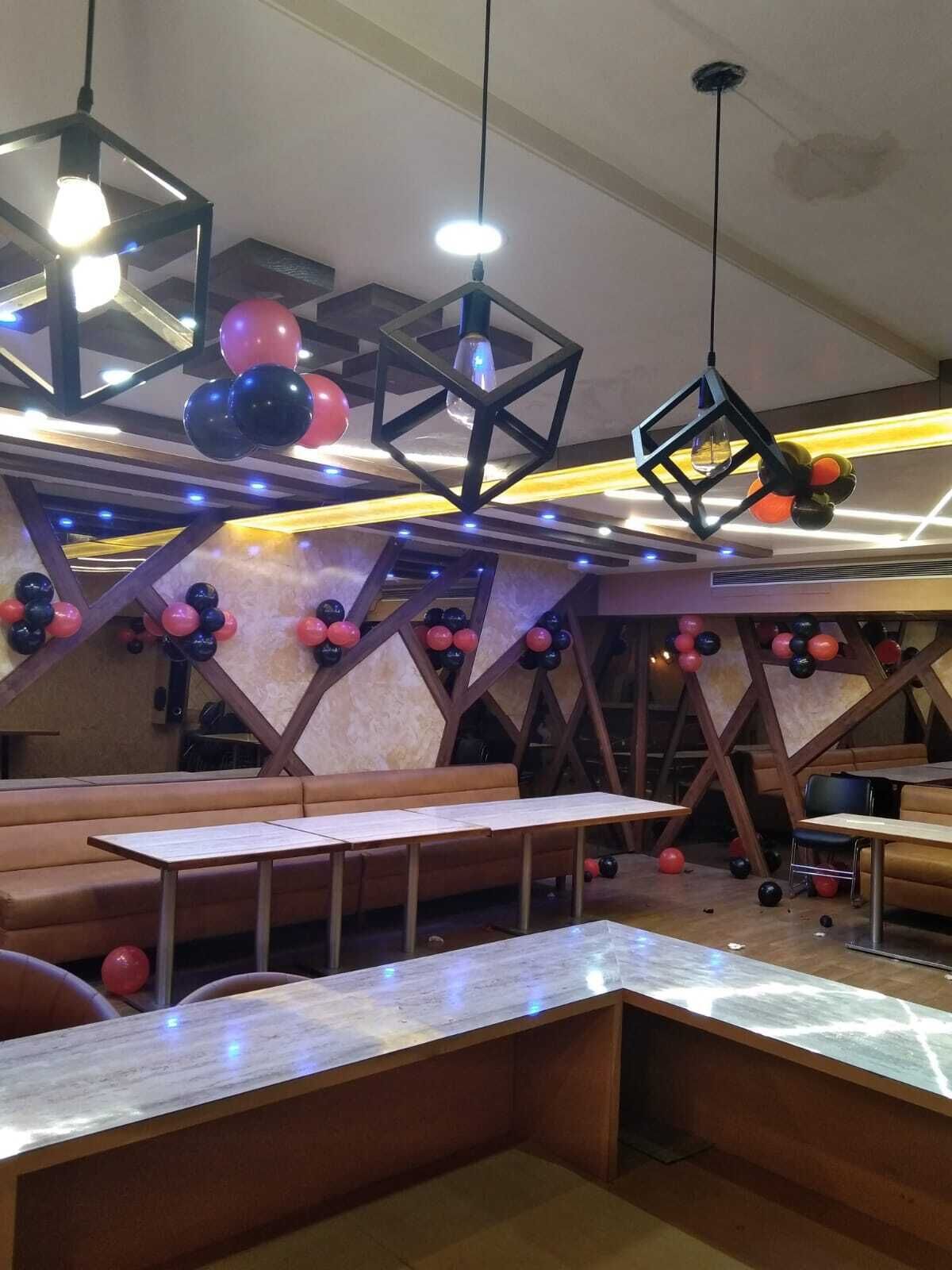 Interior de restaurante con cabinas, mesas y decoraciones esféricas colgantes.