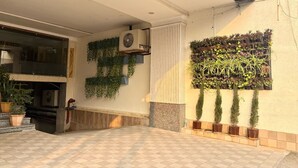 Un espacio exterior moderno con suelo de cuadros, un jarrón de pared con plantas y un ventilador de techo.