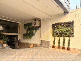 Un espacio exterior moderno con suelo de cuadros, un jarrón de pared con plantas y un ventilador de techo.