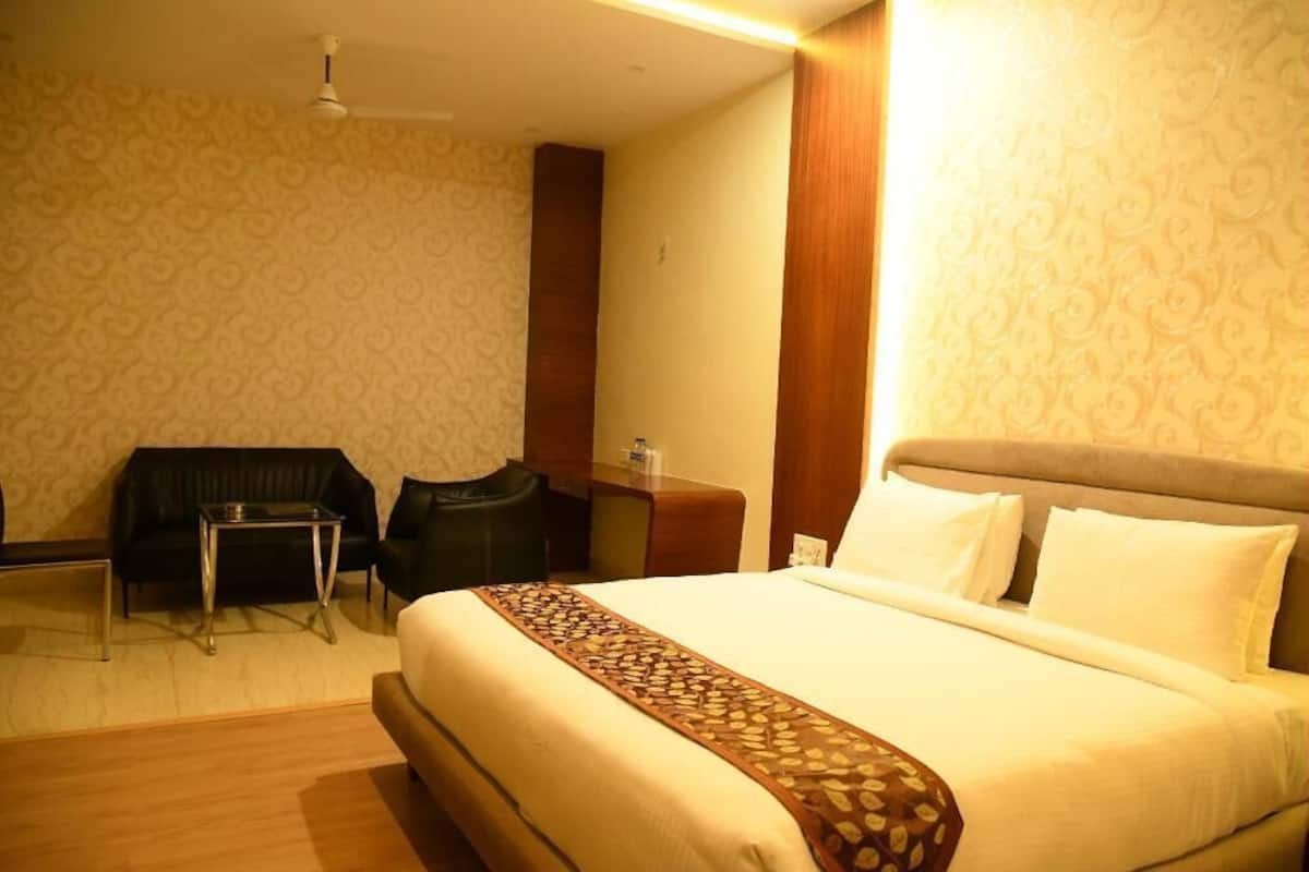 A hotel room with a bed, a desk, a chair, and a sofa.