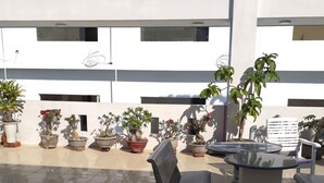 An outdoor seating area with potted plants, a bench, and a table.