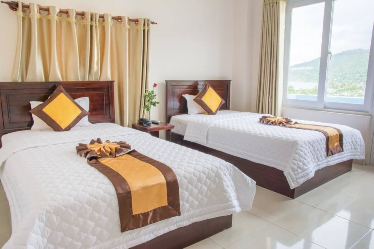 A hotel room with two beds, each with a wooden headboard and white bedding.