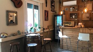 A rustic kitchen with wooden bar stools, a large wooden barrel, and a vintage radio. - Hotel Riva (Rimini)