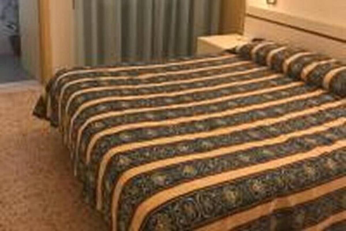 A hotel room with a bed, curtains, and a nightstand.