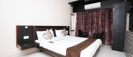 A modern bedroom with a large bed, a desk, and a chair.