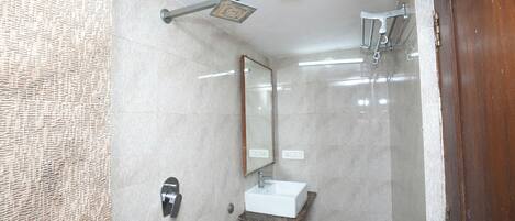 Une salle de bain équipée d’une douche, d’un lavabo, d’un miroir et d’un porte-serviettes.