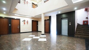 A spacious lobby with a marble floor, wooden doors, and a staircase. - HOTEL MADURAI (Udaipur)