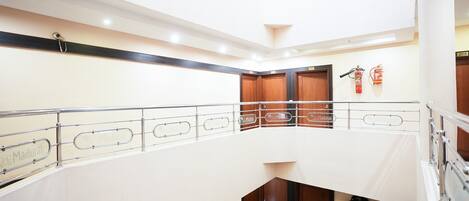 A multi-level interior with a metal railing, wooden doors, and fire extinguishers.