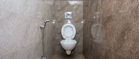 Un baño pequeño y moderno con inodoro blanco, ducha y secador de manos.