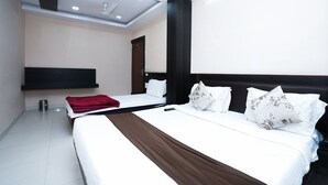 A modern hotel room with two beds, a large mirror, and a ceiling fan. - HOTEL MADURAI (Udaipur)