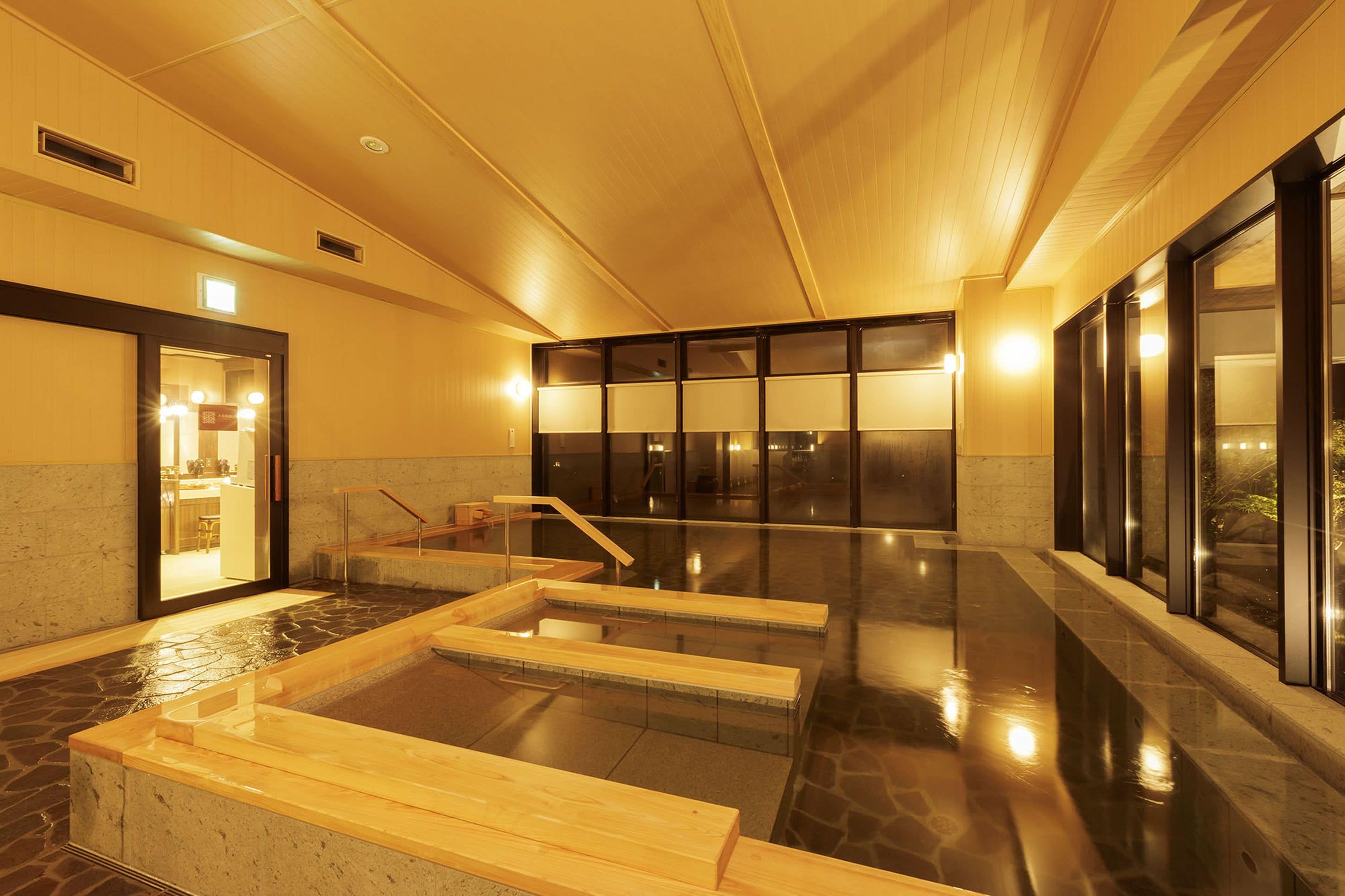 A spa area with a hot tub, wooden benches, and a stone floor.