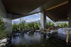 Uma área de spa com nascente termal, deck de madeira e vista para montanhas.