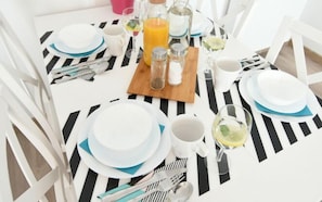 A breakfast table set with plates, cups, cutlery, and a pitcher of orange juice. - Estate Center Rooms Zajezdnia (Poznan)