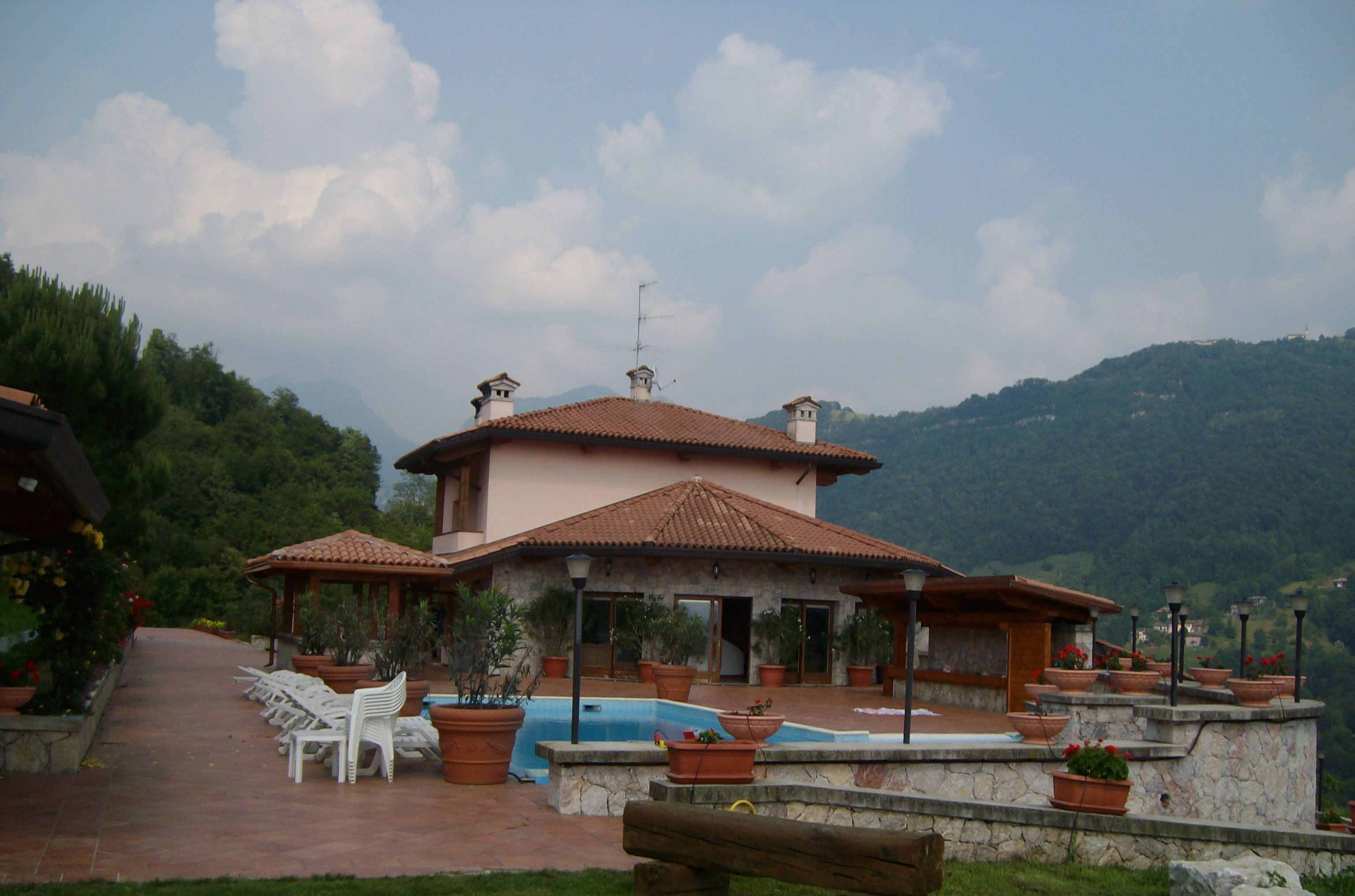 A villa with a swimming pool, outdoor seating, and a mountainous backdrop.