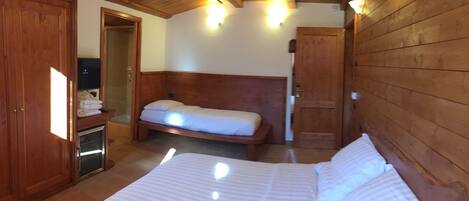 A wooden-paneled room with a bed, a small bedside table, and a door leading to a bathroom.