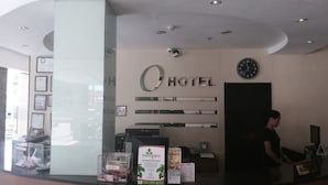 Un espace d’accueil d’hôtel comprenant un comptoir de réception, une horloge et des certificats encadrés accrochés au mur.