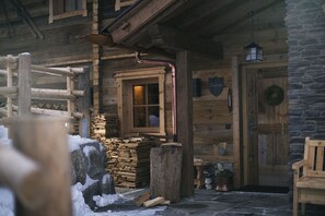 A rustic wooden cabin with a wooden door, a window, and a stone wall. - Sporer-Alm Alpine Residence (Rohrberg)