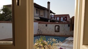 A view through a door of a room with two large white vases with flowers on a wooden table. - LilaVerde Alacati - Adults Only (Cesme)