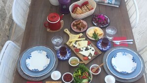 A wooden table set with various dishes, including plates, bowls, and utensils, suggesting a meal setup. - LilaVerde Alacati - Adults Only (Cesme)