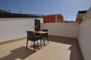 A small outdoor patio with a table and chairs, a potted plant, and a view of neighboring buildings. - Affittacamere Da Mary (Matera)