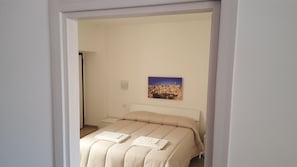 A bedroom with a bed, a wall-mounted picture, and a door leading to another room. - Affittacamere Da Mary (Matera)