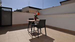 A small patio with a table and chairs, a potted plant, and a gate. - Affittacamere Da Mary (Matera)
