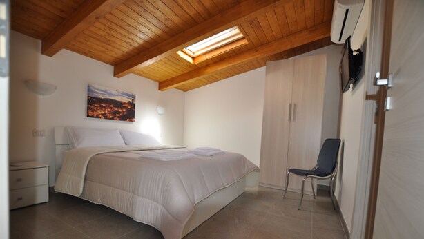 A bedroom with a bed, a chair, a nightstand, and a painting on the wall. - Affittacamere Da Mary (Matera)