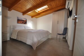 A bedroom with a bed, a chair, a nightstand, and a painting on the wall. - Affittacamere Da Mary (Matera)