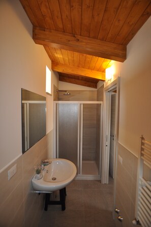 A bathroom with a wooden ceiling, a white sink, a mirror, and a shower enclosure. - Affittacamere Da Mary (Matera)