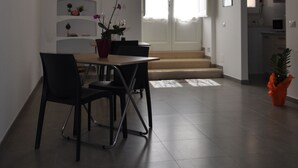 A dining area with a table and chairs, a potted plant, and a staircase leading to a second floor. - Affittacamere Da Mary (Matera)