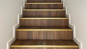 Una escalera de madera con detalles blancos y un pequeño ventanal en la parte superior.