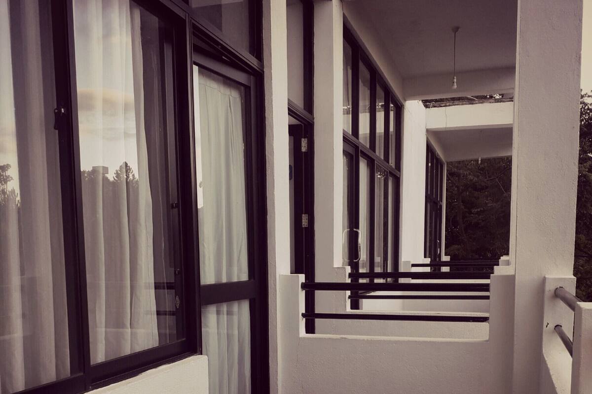 A corridor with large windows, white walls, and a black floor.