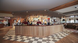 A reception area with a checkered floor, wooden reception desk, and multiple bar counters. - Spring River Ebbsfleet by Marston's Inns (Gravesend)